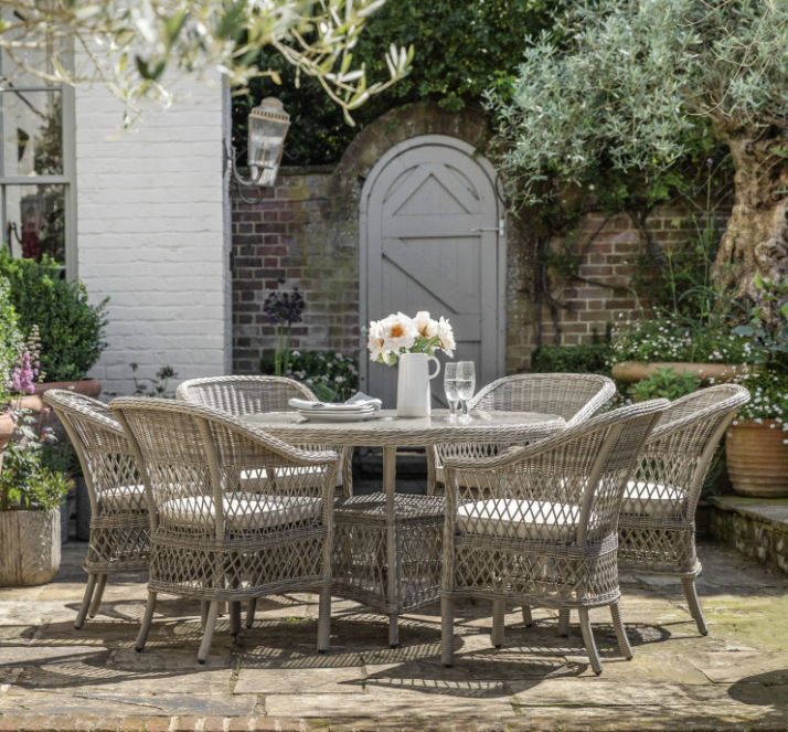 Aurina Pop UP Ltd Menton round garden dining table with six chairs, set in outdoor setting with flowers, lifestyle view